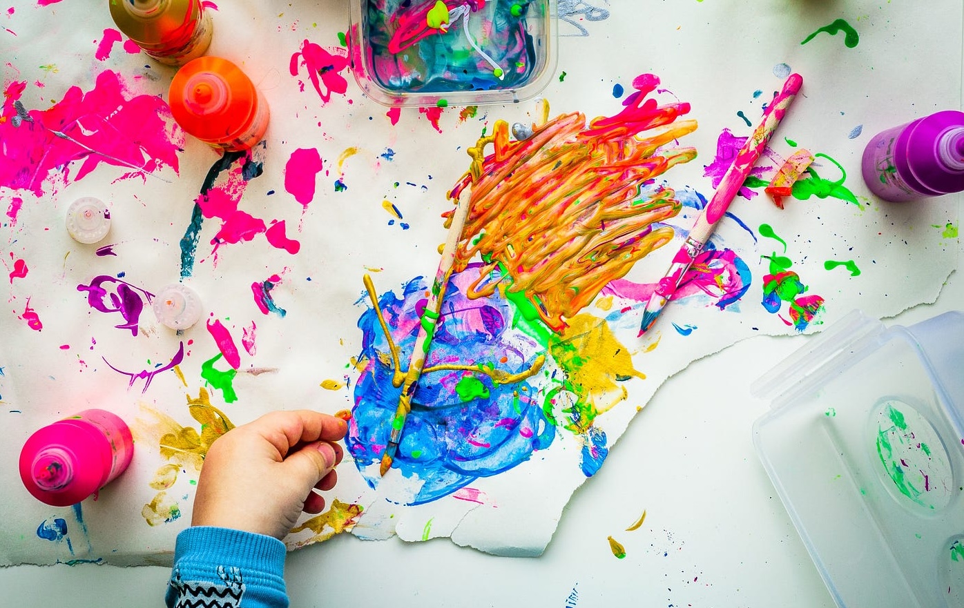 Sketches, paints, and craft tools arranged on a desk